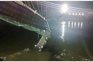 Nhiều người rớt xuống sông Machchu bên dưới khi cây cầu treo ở bang Gujarat, miền tây Ấn Độ bị sập ngày 30-10. Ảnh: REUTERS