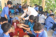 Ông Đinh Phú Cường, Hiệu trưởng Trường THCS Nguyễn Văn Luông, quận 6, đang tiếp phẩm cho học sinh trong bữa ăn bán trú. Ảnh: NGUYỄN QUYÊN