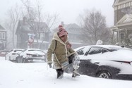 Một người phụ nữ tại TP New York, Mỹ đang chật vật đi bộ trên đường phố khi tuyết phủ dày tới đầu gối. Ảnh: AFP