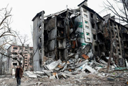 Một người đàn ông đi bộ gần một tòa nhà dân cư bị phá hủy trong cuộc xung đột Ukraine-Nga ở TP Mariupol vào ngày 17-4.
