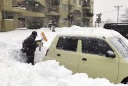 Một người dân dọn dẹp tuyết xung quanh một chiếc ô tô tại một bãi đậu xe ở TP Kitami, tỉnh Hokkaido, phía bắc nước Nhật, vào ngày 24-12.