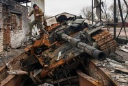 Một người đàn ông nhảy khỏi chiếc xe tăng T-72 của Nga bị phá hủy tại làng Yahidne, Ukraine ngày 20-4-2022. Ảnh: REUTERS